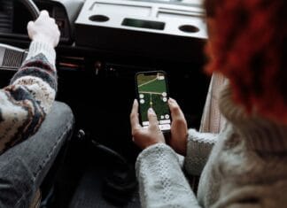 Które aplikacje z testami na prawo jazdy najlepiej odwzorowują aktualną bazę pytań Dwie osoby korzystają z aplikacji nawigacyjnej w smartfonie podczas jazdy